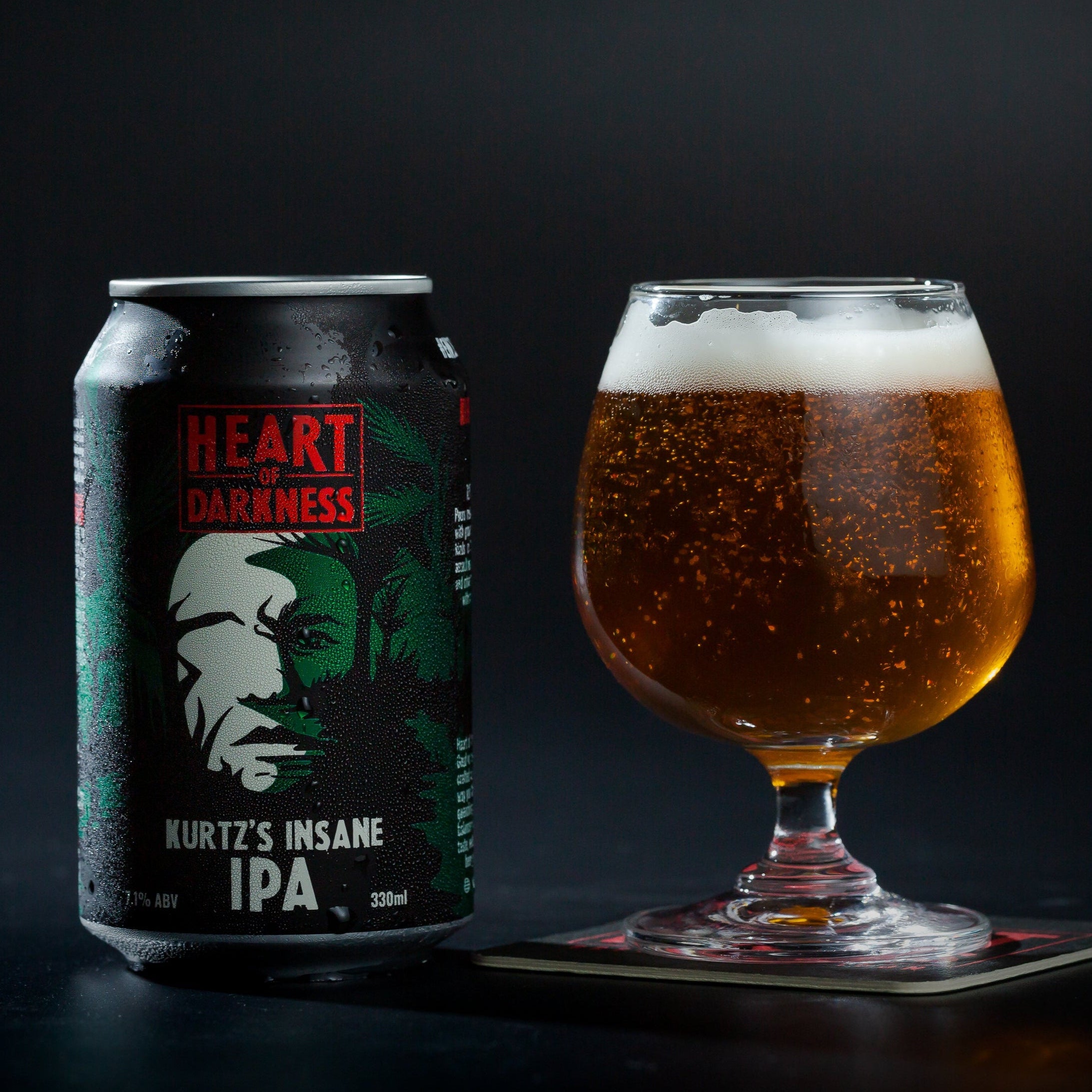 Can of Heart of Darkness Kurtz's Insane IPA next to a glass of beer on a dark background